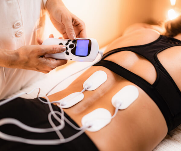 Lower Back Physical Therapy with TENS Electrode Pads, Transcutaneous Electrical Nerve Stimulation. Electrodes onto Patient's Lower Back