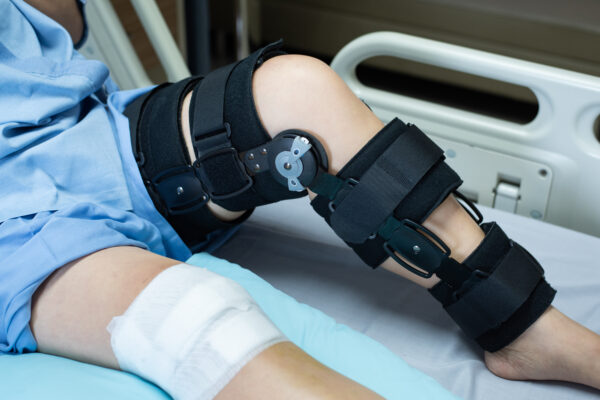 Asian woman patient with bandage compression knee brace support injury on the bed in nursing hospital.healthcare and medical support.